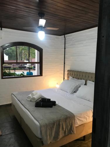 um quarto com uma grande cama branca e uma janela em Pousada dos Adris em Morretes