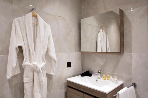 ein weißes Badezimmer mit einem Waschbecken und einem Spiegel in der Unterkunft La Residence Athens in Athen