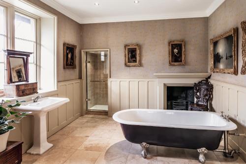 a bathroom with a tub and a sink and a fireplace at The Casterton Grange Estate in Kirkby Lonsdale