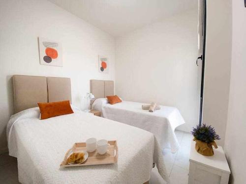 une chambre blanche avec deux lits et un plateau de nourriture dans l'établissement Groundfloor Pink Ciñuelica -Winter by the sea, à Orihuela Costa