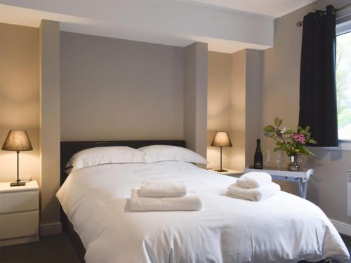 a bedroom with a large white bed with towels on it at The Lodge at Braemor in Arrochar