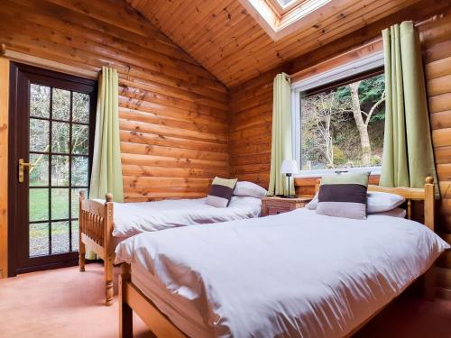 dwa łóżka w drewnianym domku z oknami w obiekcie Ard Darach Lodge w mieście Brinscall