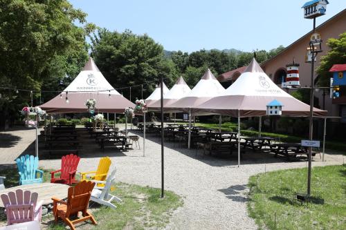 eine Gruppe von Tischen und Stühlen mit Sonnenschirmen in der Unterkunft Kensington Resort Gapyeong in Gapyeong