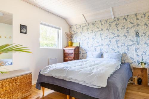 a bedroom with a bed and a wall with a bird wallpaper at Modern and cozy cabin near Copenhagen city and airport in Dragør