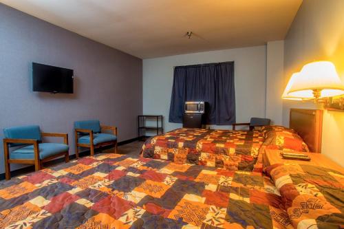 een hotelkamer met een bed en twee stoelen bij Lafayette Inn in Moundsville