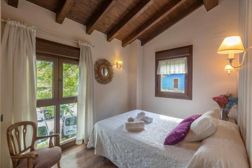 Un dormitorio con una cama con almohadas moradas y una ventana en Casa de aldea el Toral, en Rales
