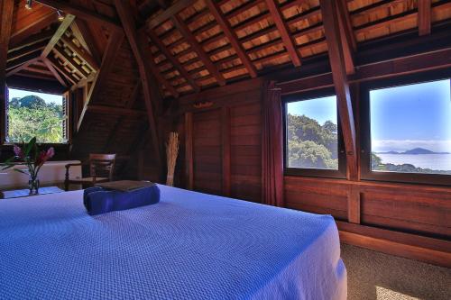a bedroom with a bed in a room with windows at Jardin Malanga in Basse-Terre
