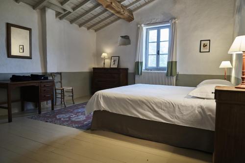 1 dormitorio con cama, escritorio y ventana en La Cour du Marronnier, en Pont-de-Barret