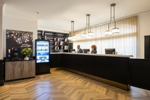 a lobby with two people sitting at a counter at The President Brussels Hotel in Brussels