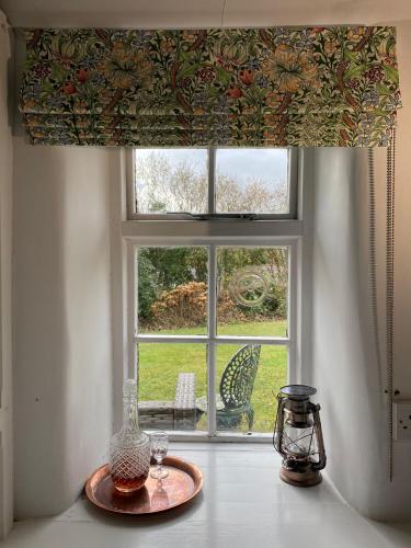 a window with a view of a garden from a table with a window shade at The Crown Inn in Lanlivery