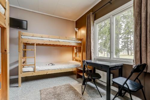 1 Schlafzimmer mit Etagenbetten, einem Schreibtisch und einem Fenster in der Unterkunft STF Hostel Lärbro/Grannen in Lärbro