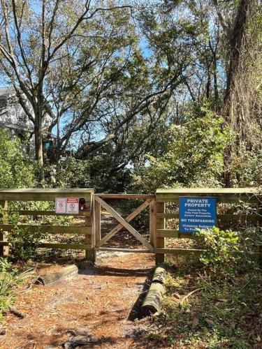 a wooden fence with a gate with a sign on it at Renovated Cottage: 4th row from the Beach! in Hilton Head Island