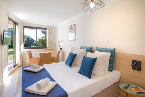 a bedroom with a white bed with blue and white pillows at SOWELL Family Port Grimaud in Grimaud