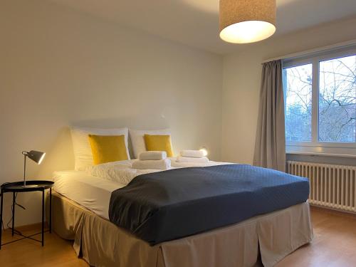 a bedroom with a large bed with yellow pillows at Comfort 1 and 2BDR Apartment close to Zurich Airport in Zürich