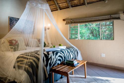 侯斯普瑞特的住宿－Sunbirds Oasis Lodge，一间卧室配有一张带蚊帐的床