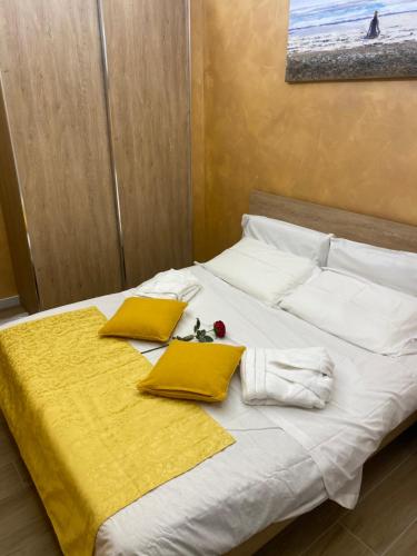 a bed with yellow and white pillows on it at Appartamento feriolo Margherita in Baveno