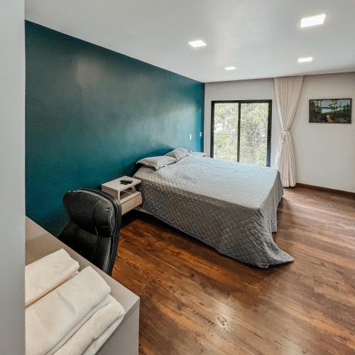 a bedroom with a bed and a chair and a couch at Casa Recanto da Neblina in Petrópolis