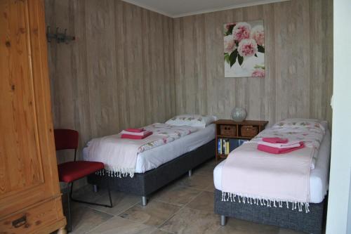a bedroom with two beds and a red chair at B&B de Linde in Hoogeveen