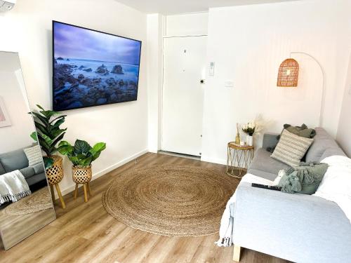 ein Wohnzimmer mit einem Sofa und einem TV an der Wand in der Unterkunft Moonee Ponds’ hidden gem – 1BR w/ Free Parking in Melbourne