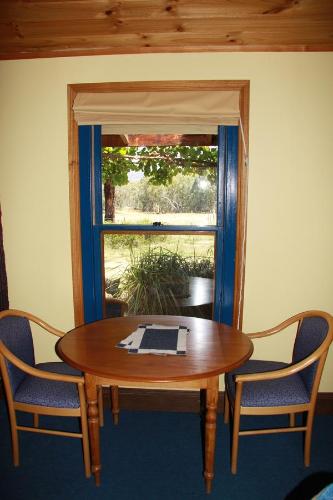 una mesa de madera con 2 sillas y una ventana en Candlebark Retreat, en Beechworth