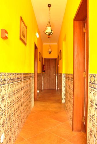 a hallway with yellow walls and tile floors at Hospedaria Pielas in Sintra