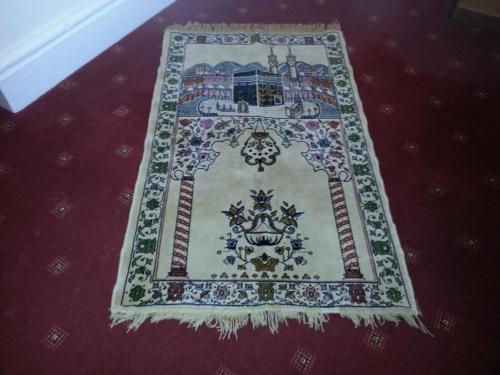 a rug on a red carpet with a picture on it at Arman Lodge House in Peterborough
