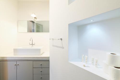 biała łazienka z umywalką i lustrem w obiekcie Duomo Luxury Apartment VIII w Mediolanie