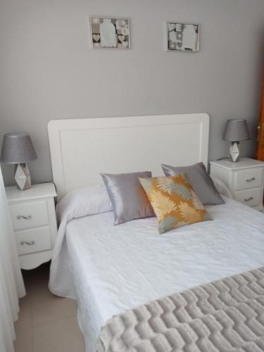 1 cama blanca con 2 mesitas de noche y 2 lámparas en Apartamento Combarro Ángeles, en Combarro