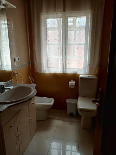 baño con lavabo y aseo y ventana en Apartamento Combarro Ángeles, en Combarro