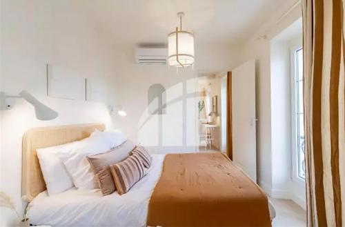 - une chambre avec un lit aux murs blancs et un lustre dans l'établissement 2 pièces vieux Nice vue coulée verte, à Nice