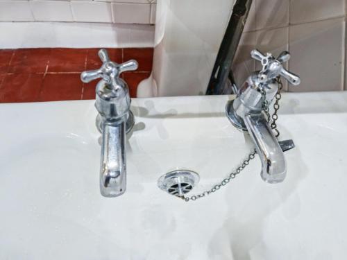 two silver faucets on a white sink at Cosy Penicuik Apartment in Penicuik