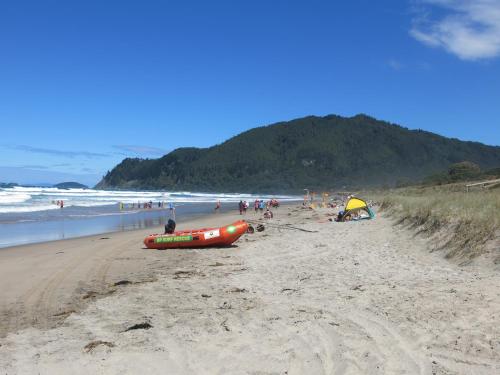 a group of people on a beach with a boat at Ocean Breeze Resort Pauanui in Pauanui