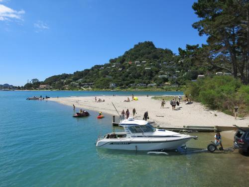 a boat docked at a beach with people on it at Ocean Breeze Resort Pauanui in Pauanui