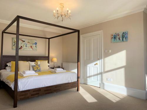 a bedroom with a canopy bed and a chandelier at Balmeadowside Farmhouse with Hot Tub in Cupar