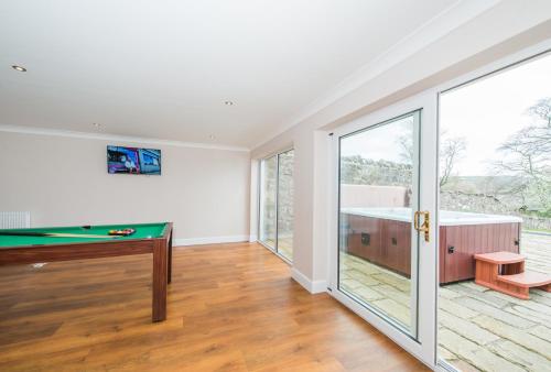 an empty room with a pool table and sliding glass doors at Balmeadowside Farmhouse with Hot Tub in Cupar