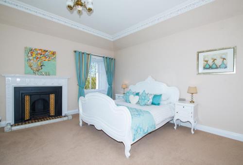a bedroom with a white bed and a fireplace at Balmeadowside Farmhouse with Hot Tub in Cupar