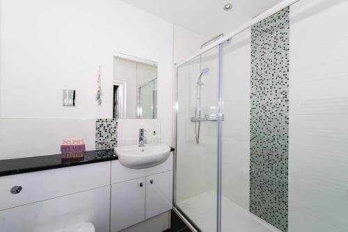 a white bathroom with a sink and a shower at Balmeadowside Farmhouse with Hot Tub in Cupar