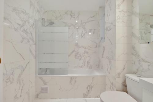 a white bathroom with a tub and a toilet at Eiffel Tower view Residence in Paris