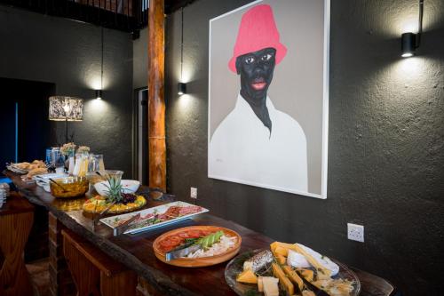 a table topped with plates of food with a person wearing a black mask at Sunbirds Oasis Lodge in Hoedspruit