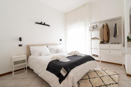 a white bedroom with a bed with a black and white blanket at Hotel Adriatica con Piscina in Riccione