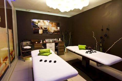 two white beds in a room with green pillows at Hotel Zimnik Luksus Natury Spa & Wellness in Szczyrk