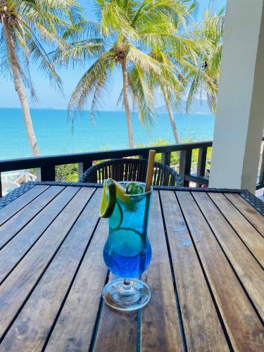a blue glass sitting on a wooden table with the beach at Paradise Resort Doc Let - All Inclusive in Doc Let