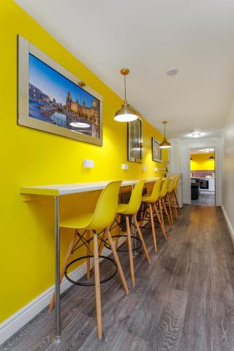 a dining room with yellow walls and a table and chairs at Snuggle Cove Apartments By Bella Vita Stays in Liverpool