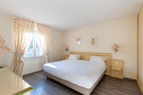 a bedroom with a white bed and a window at Residhotel Golf Grand Avignon in Vedène