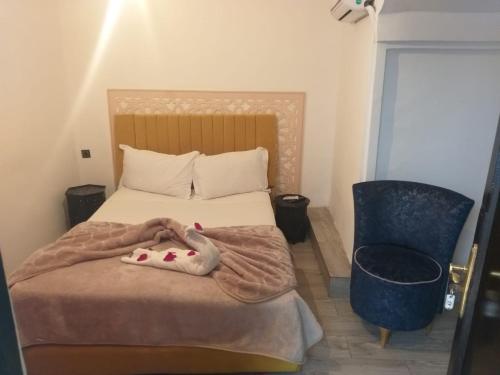 een slaapkamer met een bed met een deken en een stoel bij Hôtel Agnaou in Marrakesh