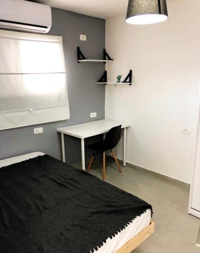 Schlafzimmer mit einem Bett, einem Schreibtisch und einem Fenster in der Unterkunft Pninat Hadrom in Be’er Scheva