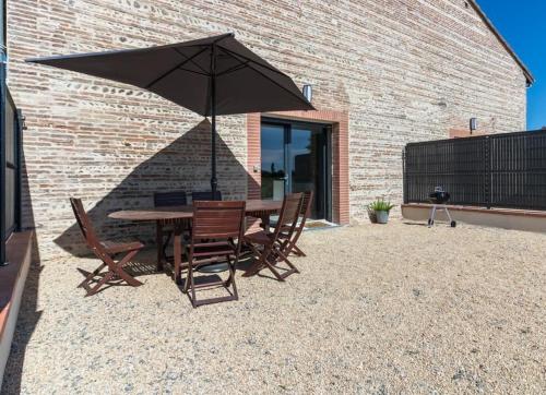 a table and chairs with an umbrella on a patio at Domaine le Caprougeat in Daux