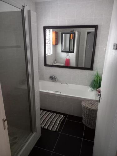 a bathroom with a bath tub and a mirror at Chardonnay Holiday Apartment in Jeffreys Bay