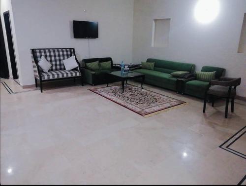 Capry Guest House في كراتشي: غرفة معيشة مع أريكة وكراسي خضراء