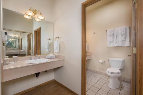 a bathroom with a sink and a toilet and a mirror at The Pines Resort & Conference Center in Bass Lake